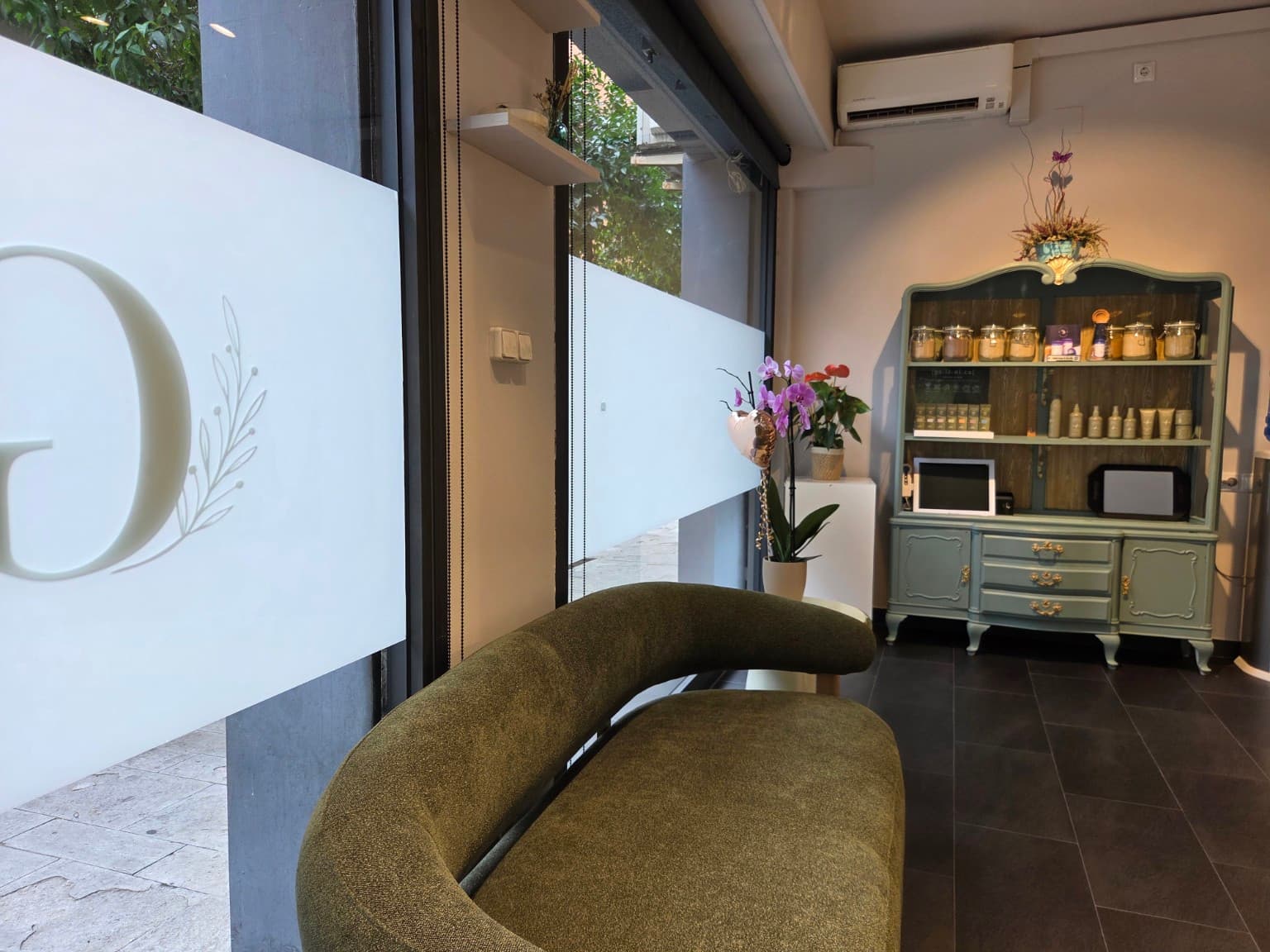 Zona de espera de Gio Studio con sofá verde, orquídea y aparador